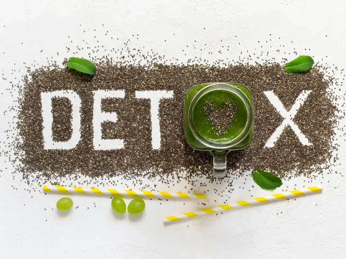 Green smoothie with chia seeds spelling the word detox, with mint leaves and green grapes